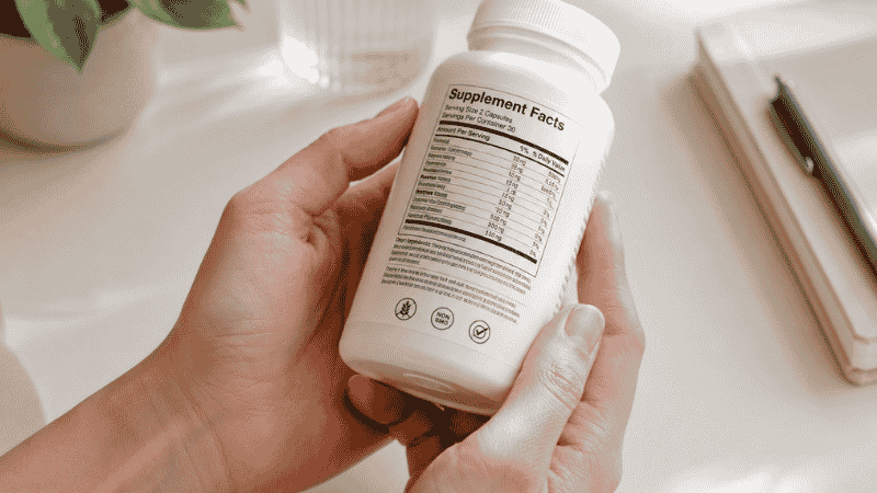 Person reading the Supplement Facts label on a magnesium glycinate bottle to check elemental magnesium dosage