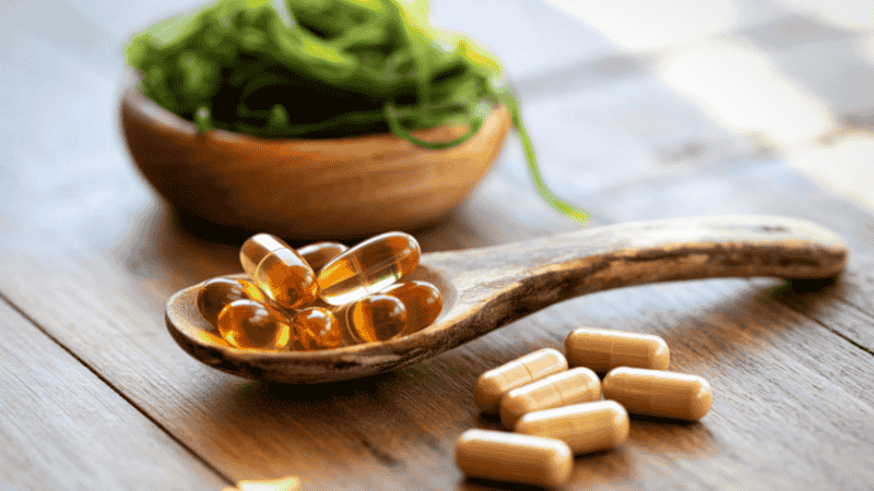 A macro shot of golden Omega-3 fish oil softgels and botanical capsules, highlighting the importance of ingredient purity and standardized extracts in dietary supplements.