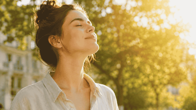 Person standing in warm sunlight outdoors representing the combined benefits of sunlight exposure and proper vitamin D supplementation for overall health