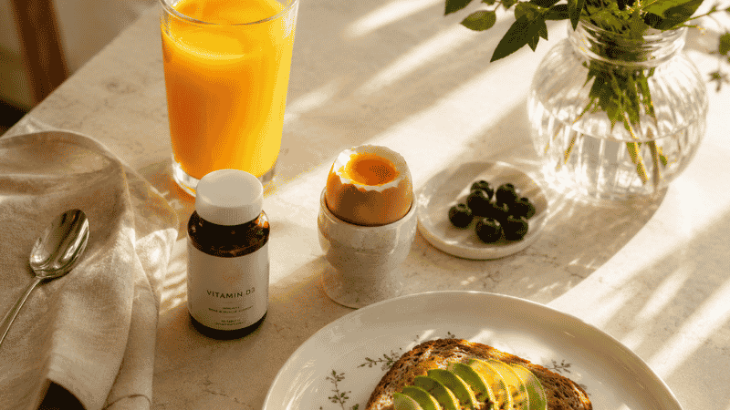 Morning breakfast table with supplement bottle showing the recommended timing for taking vitamin D in the morning with food for better sleep support