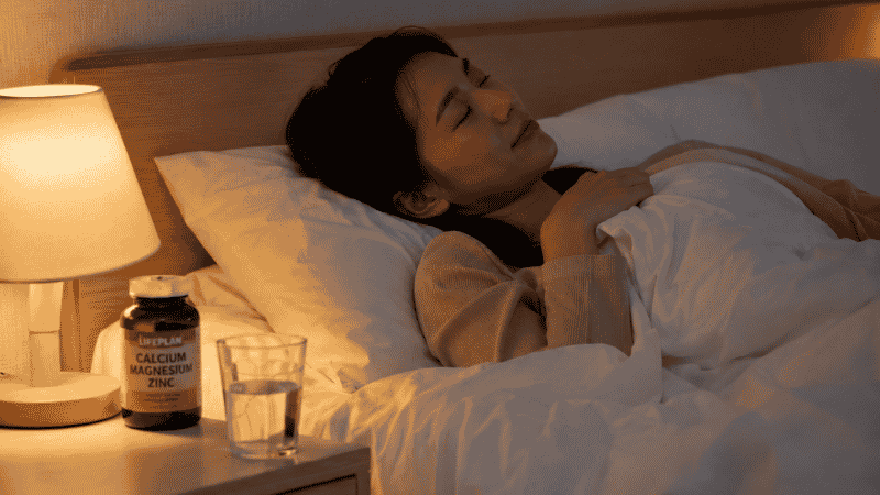 Person resting peacefully in bed at night with magnesium supplement on nightstand